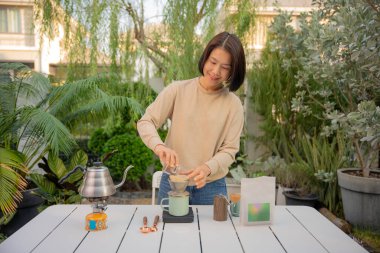 Asyalı bir kadın evinin bahçesinde kahve çekirdeği damlatıyor..