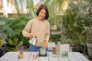 Asyalı bir kadın evinin bahçesinde kahve çekirdeği damlatıyor..