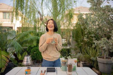 Asyalı bir kadın evinin bahçesinde kahve çekirdeği damlatıyor..