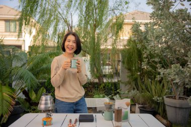 Asyalı bir kadın evinin bahçesinde kahve çekirdeği damlatıyor..