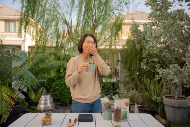 Asyalı bir kadın evinin bahçesinde kahve çekirdeği damlatıyor..