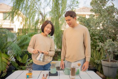 Çift mutlu bir şekilde bahçede birlikte kahve yapıyor..