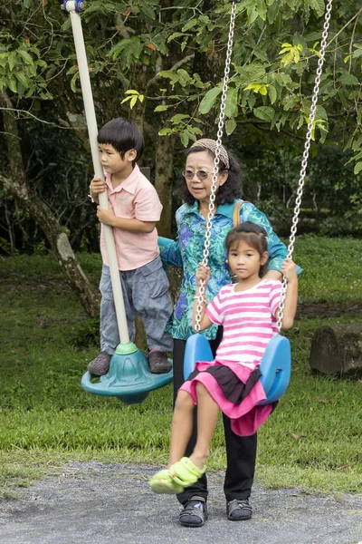 Азиатская семья на качелях в парке — стоковое фото