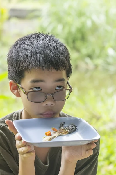 Ragazzo pensieroso guarda osso di pesce mangiato chiaramente sul piatto — Foto Stock