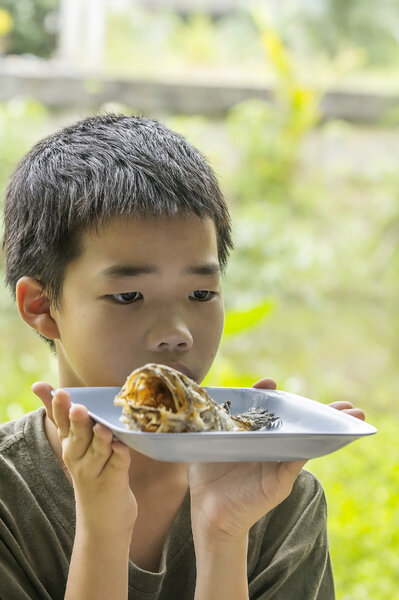 Pensive boy looks at fish bone eaten clearly on plate