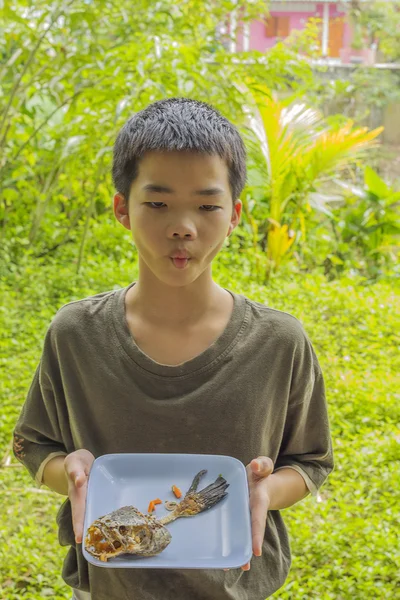 Nadenkend boy kijkt vis bot gegeten duidelijk op plaat — Stockfoto