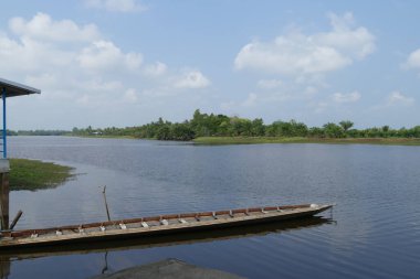 Nehirdeki ahşap tekne Tayland 'ın doğası ve mavi gökyüzü, yazın rıhtımdan nehre manzara