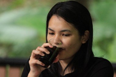 Genç Asyalı kadın Tayland 'da bir restoranda kahve içiyor..