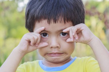 Mutlu Asyalı şirin Taylandlı çocuğun portresi parmaklarıyla gözlerini yuvarlıyor.