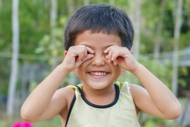 Mutlu Asyalı şirin Taylandlı çocuğun portresi parmaklarıyla gözlerini yuvarlıyor.