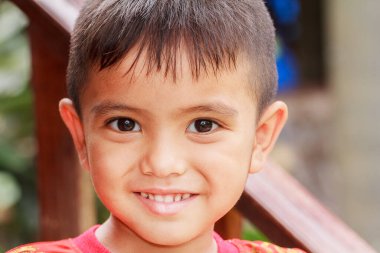 Kapalı alanda gülümseyen Asyalı küçük çocuğun şirin portresi.