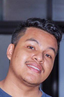 Asyalı genç adam içeride gülümsüyor.