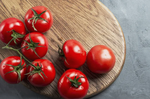 Yeşil dallı taze kırmızı domatesler ve tahta bir tahtanın üzerine su damlaları. Boş yer.