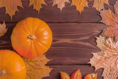 Olgun balkabaklarının ve sonbahar yapraklarının ahşap arka planda üst görüntüsü. Boşluğu kopyala.