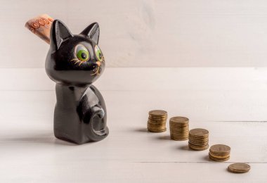 Beş bininci banknotla birlikte kumbaraya giden bozuk para kolonları. Tasarruf ve tasarruf kavramı. Kopya alanı olan tahta arkaplan.