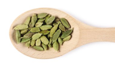 Beyaz arka planda izole edilmiş tahta kaşıkta yeşil kakule kapsülleri üst tarafta.