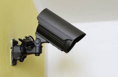Sarı duvardaki siyah Cctv kamera