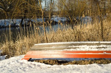 Nehir kıyısında kar altında bir tekne.
