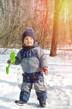 Küçük çocuk kış parkında yürüyor.