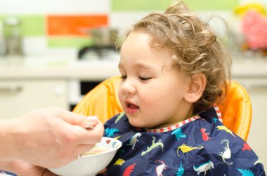 Küçük çocuk evde yemek yiyor.