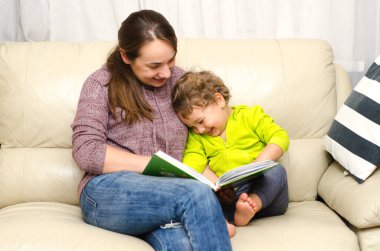 Anne ve çocuk evde kitap okuyor.