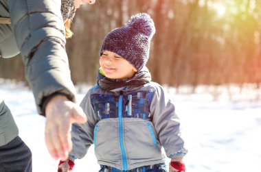 Anne, çocuğu kış parkında kucaklıyor.