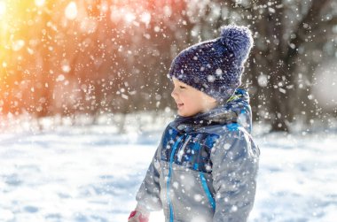 Küçük çocuk kış parkında yürüyor.