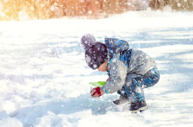 Küçük çocuk kış parkında yürüyor.