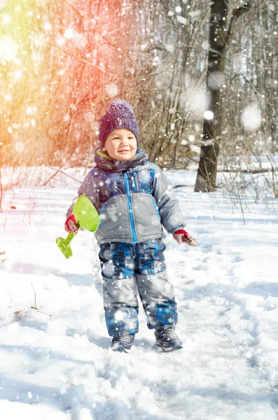 Küçük çocuk kış parkında yürüyor.