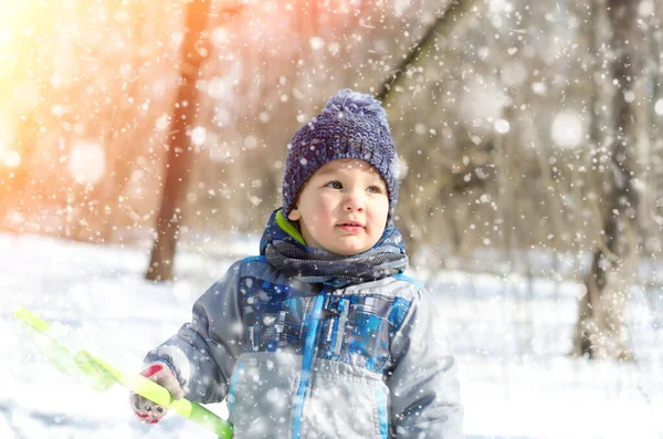 Küçük çocuk kış parkında yürüyor.