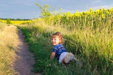 Küçük çocuk tarlada yatıyor.