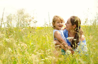 Anne ve çocuk güneşli çayırda