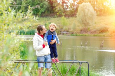 Anne ve çocuk güzel göletin yanında duruyor.