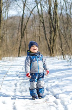 Küçük çocuk kış parkında yürüyor.
