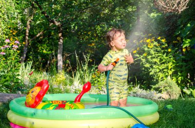 Küçük çocuk havuzda oynuyor.
