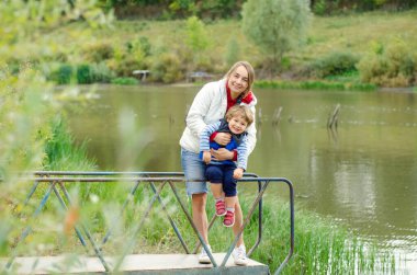 Anne ve çocuk güzel göletin yanında duruyor.