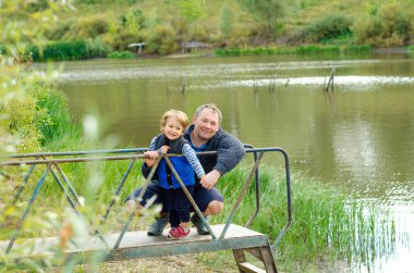 Baba ve oğul güzel bir göletin kenarında oturuyor.