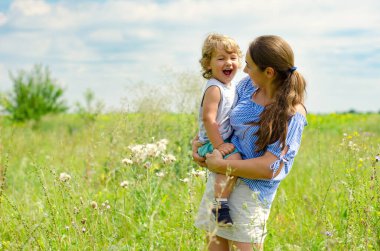 Anne ve çocuk güneşli çayırda