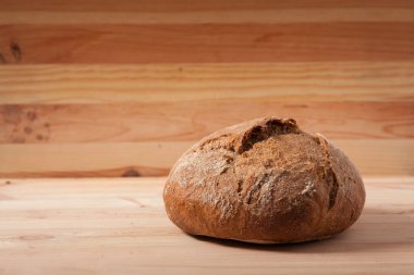 Sabah ışığında ahşap zemin üzerinde el yapımı taze buğday ekmeği. metin veya tasarım için boşluk alanı ile yatay çerçeve yan görünümü