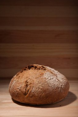 Kontrastlı ışıkta ahşap zemin üzerinde el yapımı taze buğday ekmeği. metin veya tasarım için alan alanı ile dikey çerçeve kenar görünümü