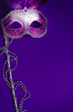Purple Mardi-Gras or Venetian mask on purple background clipart