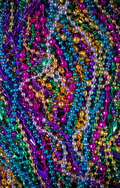 A background of  brightly colored Mardi-Gras beads on a purple b — Stock Photo, Image