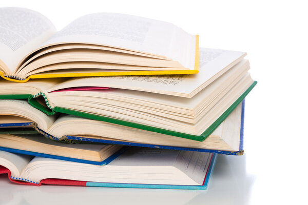 A stack of colorful, open books on a white background