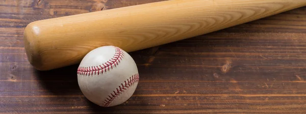 Un bate de béisbol de madera y una pelota sobre un fondo de madera —  Fotos de Stock