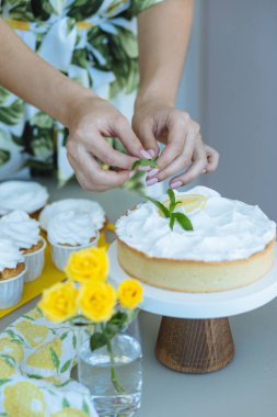 Pasta şefinin elleri limonlu turtayı krema, nane ve limonlu gri masada limonlu kekle süsler. Konsept: Pastane veya kahvaltı