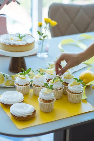 Pasta şefi, limon kreması, nane ve limon dilimleri ile pişirilmiş kekleri ya da masa, pasta ve çiçek vazosunun arka planında kutlamayı süslüyor