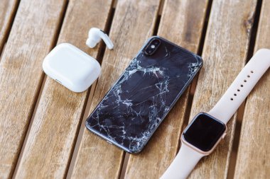 Gelendzhik, Rusya, 29 / 07 / 2020: Kırık camlı iPhone kulaklıklar ve Applewatch 'ın yanında yer alıyor