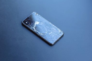 Gelendzhik, Rusya, 07 / 29 / 2020: Kırık sırt kapağı çatlak ve çiplerle kaplı iPhone koyu metal masa yüzeyinde yatıyor