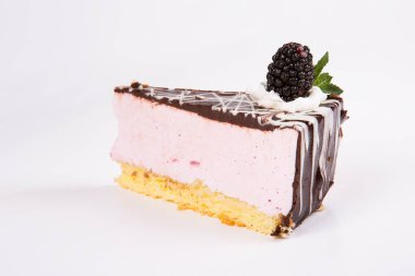 Çikolata, böğürtlen ve nane ile süslenmiş beyaz tabakta çilekli yoğurtlu pasta. Bisküvili kek dilimi. Çocuk oyuncağı. Seçici odak.