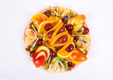 Çeşitli taze meyveler güzel dilimlenmiş ve ahşap tahtada servis edilmiş. Üst manzarayı kapatın. Mevsimlik meyveler: elma, muz, portakal, üzüm, kivi